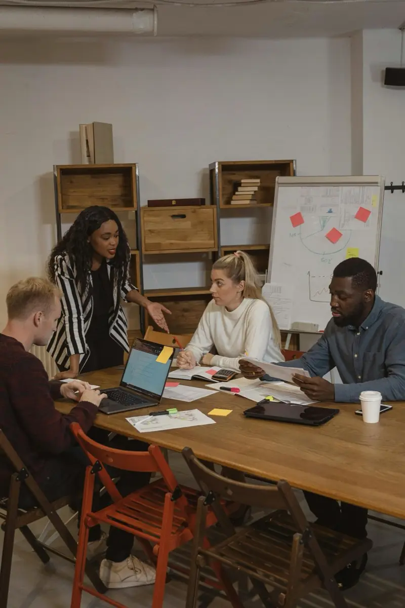 A team meeting around a table with laptops and notes